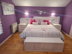 a purple bedroom with a white bed and purple walls at Casa familiar katandres in San Mamés de Meruelo
