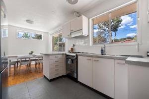 a kitchen with white cabinets and a large window at Comfortable Home for 6 - Canberra Inner North in Belconnen