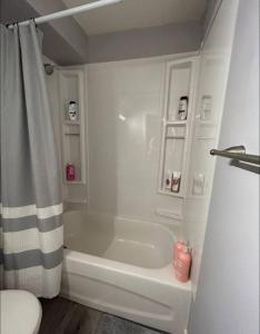 a white bathroom with a tub and a toilet at Spacious and cute basement unit in Thunder Bay