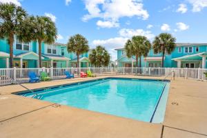 a swimming pool with palm trees and blue condos at La Concha Cottage in Port Aransas