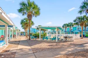 a walkway in front of blue houses with palm trees at La Concha Cottage in Port Aransas
