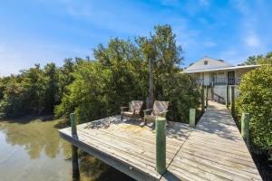 a dock with two chairs and a house at A Cedar Key Dock Holiday! in Cedar Key