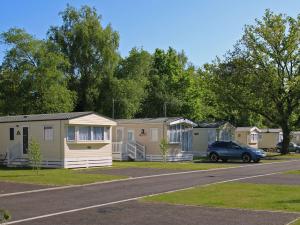 a row of mobile homes parked in a parking lot at 1. Forest Edge 2 Bedroom Statement Caravan in Saint Leonards