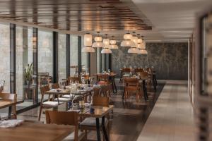 a restaurant with wooden tables and chairs and windows at Devossion By Live Aqua Playa del Carmen All Inclusive - Adults Only in Playa del Carmen