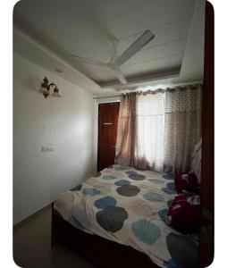 a bedroom with a bed with a comforter and a window at E block in Rājpur