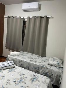 a room with two beds and a window with curtains at suite privativa centro de Dourados in Dourados +19 photos