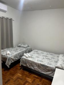 two twin beds in a room withthritisthritisthritisthritisthritisthritisthritisthritisthritis at suite privativa centro de Dourados in Dourados