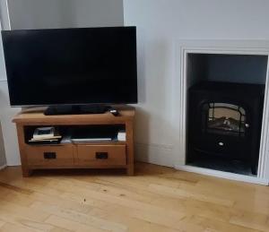 a flat screen tv on a stand with a fireplace at Clare Cottage in Doolin