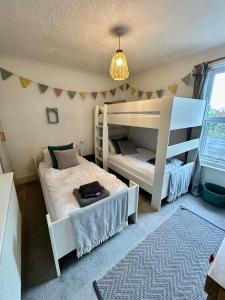 a bedroom with two bunk beds and a chandelier at Sea Song Cottage in Broadstairs