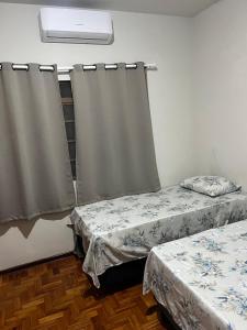 a room with two beds and a window with curtains at suite privativa centro de Dourados in Dourados