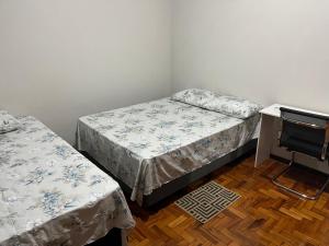 a bedroom with two beds and a desk with a chair at suite privativa centro de Dourados in Dourados
