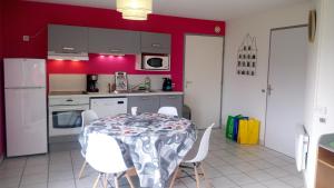 a kitchen with a table with white chairs and red walls at Les Clés Nature Apt 44 in Moutiers-sous-Chantemerle