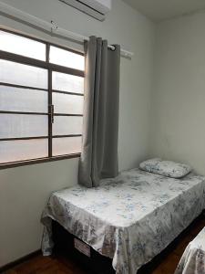 a bed in a room with a window at suite privativa centro de Dourados in Dourados