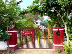 a red gate with a sign on it next to trees at The ROYAL OASIS in Khetri +1 photo