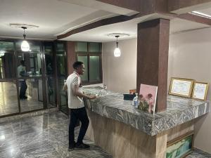 a man standing at a counter in a hotel lobby at Ngueye Hotel in Yaoundé