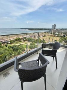 a balcony with two chairs and a view of the ocean at Milord Suites & Apartments in Encarnación