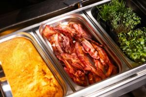 a tray of food with bacon and some broccoli at Hotel Vestmannaeyjar in Vestmannaeyjar