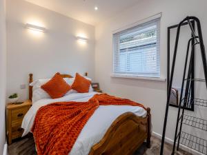 a bedroom with a bed with an orange blanket on it at Sunrise Cottage in Berwick-Upon-Tweed +14 photos