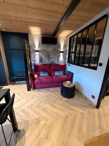 a living room with a red couch and a table at Le Petit Nid D'Amour in Évans