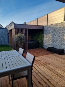a patio with a table and chairs on a wooden deck at Le Petit Nid D'Amour in Évans