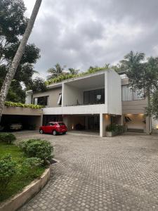 a white house with a red car parked in a driveway at Lumiere Villa, Kandy in Nugawela