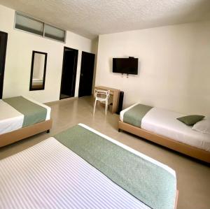 a hotel room with two beds and a flat screen tv at HOTEL CATALUÑA PEREIRa in Pereira