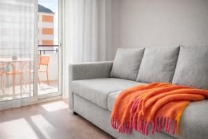 an orange blanket sitting on a couch in a living room at Beachfront apartment with sea views in Cunit +1 photo