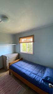 a bedroom with a blue bed and a window at Cabañas Arte Patagonia in Puyehue