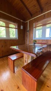 a large wooden table in a room with benches at Cabañas Arte Patagonia in Puyehue