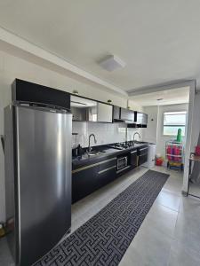 a kitchen with a stainless steel refrigerator and a rug at Apto 83 in Itanhaém +4 photos