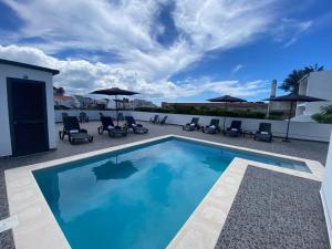 a swimming pool with chairs and umbrellas on a patio at The Rock Hostel in Ponta Delgada