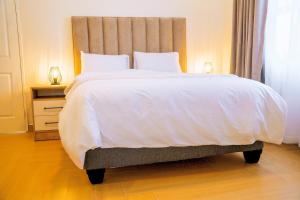 a bedroom with a large bed with white sheets and pillows at Sunderdale in Gweru