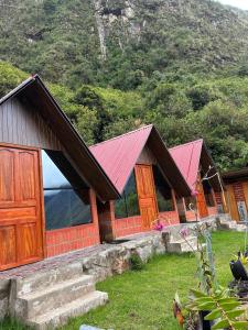a row of wooden cabins with red roofs at AndeStay Hostel Colpapampa in Colcapampa