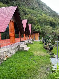 a row of buildings with red roofs on a mountain at AndeStay Hostel Colpapampa in Colcapampa