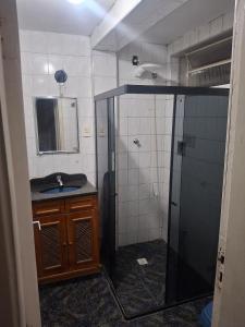 a bathroom with a shower and a sink and a mirror at Aconchego in Juiz de Fora