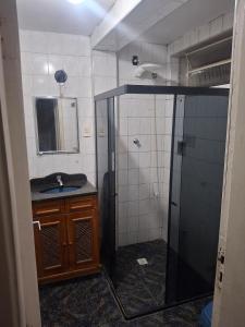 a bathroom with a shower and a sink and a mirror at Aconchego in Juiz de Fora