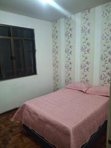 a bedroom with a bed with pink sheets and a window at Aconchego in Juiz de Fora
