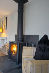 a stove in a living room with a couch and a fireplace at Pen-Y-Worlod Cottages in Abergavenny