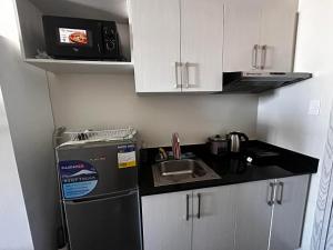 a small kitchen with a sink and a refrigerator at Orwell Heights-Vista Recto in Manila