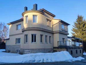a large building with snow in front of it at Vila Victory polopenze v Krušných horách in Abertamy