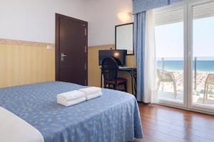 a bedroom with a bed with a desk and a balcony at Hotel Regina Fronte Mare in Rimini