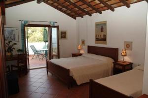 a bedroom with two beds and a door to a patio at Punto de Vista B&B Makari in San Vito lo Capo