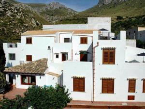 a white house with brown windows and mountains in the background at Punto de Vista B&B Makari in San Vito lo Capo