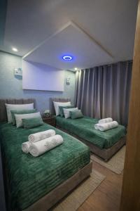 two beds in a room with green sheets and white pillows at Prime stay downtown Meknes in Meknès