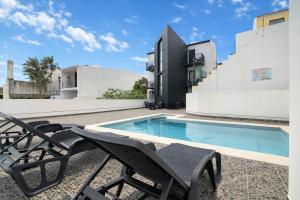 a swimming pool with chairs next to a building at The Rock Hostel in Ponta Delgada