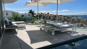 a patio with chairs and an umbrella and a pool at Luxurious villa with ocean views in Callao Salvaje