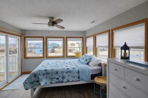 a bedroom with a bed with a blue blanket and windows at KH4112-Resting Beach Face in Kitty Hawk +20 photos