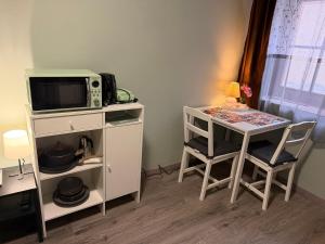 a kitchen with a microwave and a table with chairs at La Casa de Nido - Mini Studio in Veszprémfajsz