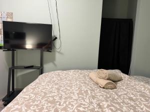 a towel laying on a bed with a flat screen tv at La Casa de Nido - Mini Studio in Veszprémfajsz