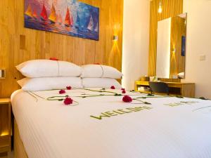 a white bed with red flowers on top of it at Serenity Stay in Huraa